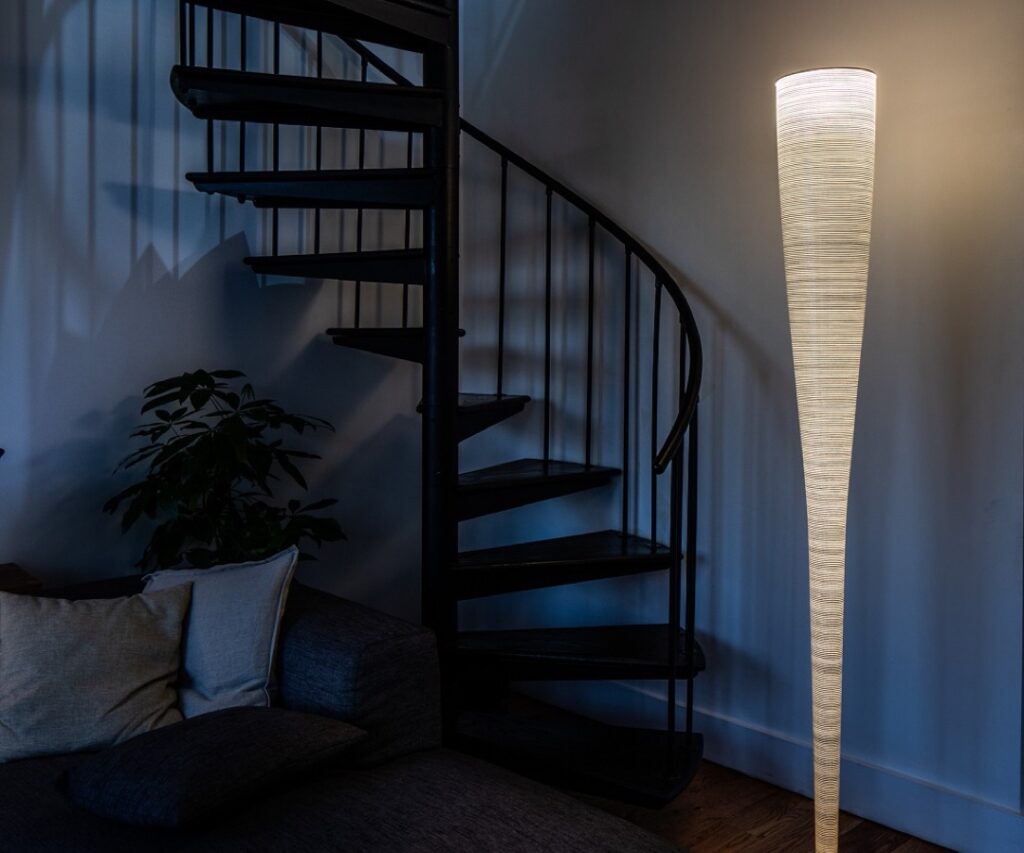 Mite golvlampa från Foscarini - lampan visar en trappa, soffa och golvlampa med en fin ljusbild mot vägg och tak.