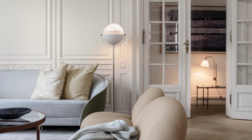 Bilden visar Multi-lite golvlampa, BL1 bordslampa, en soffa och fotöljer från varumärket Gubi.